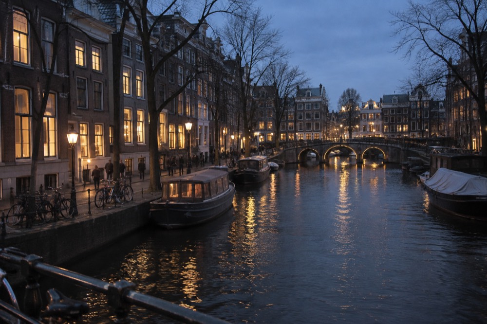 Amsterdam canal at dusk in winter with warm window lights reflecting on dark water