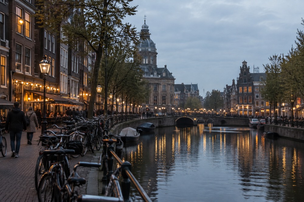 Evening street in Amsterdam with lit restaurant windows and bicycles parked along the canal