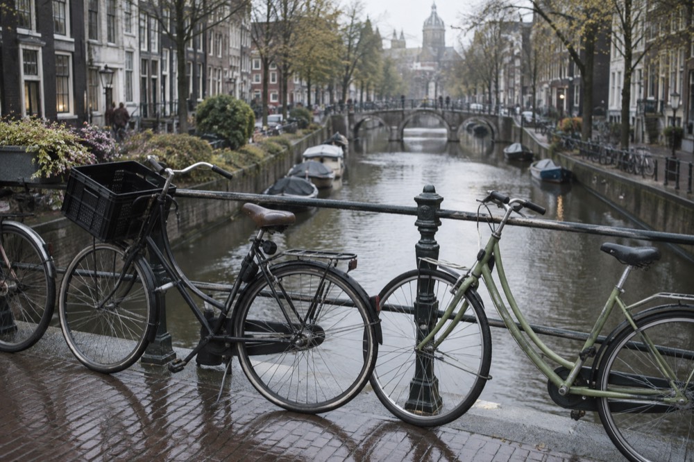 Bicycles parked on a bridge railing over an Amsterdam canal