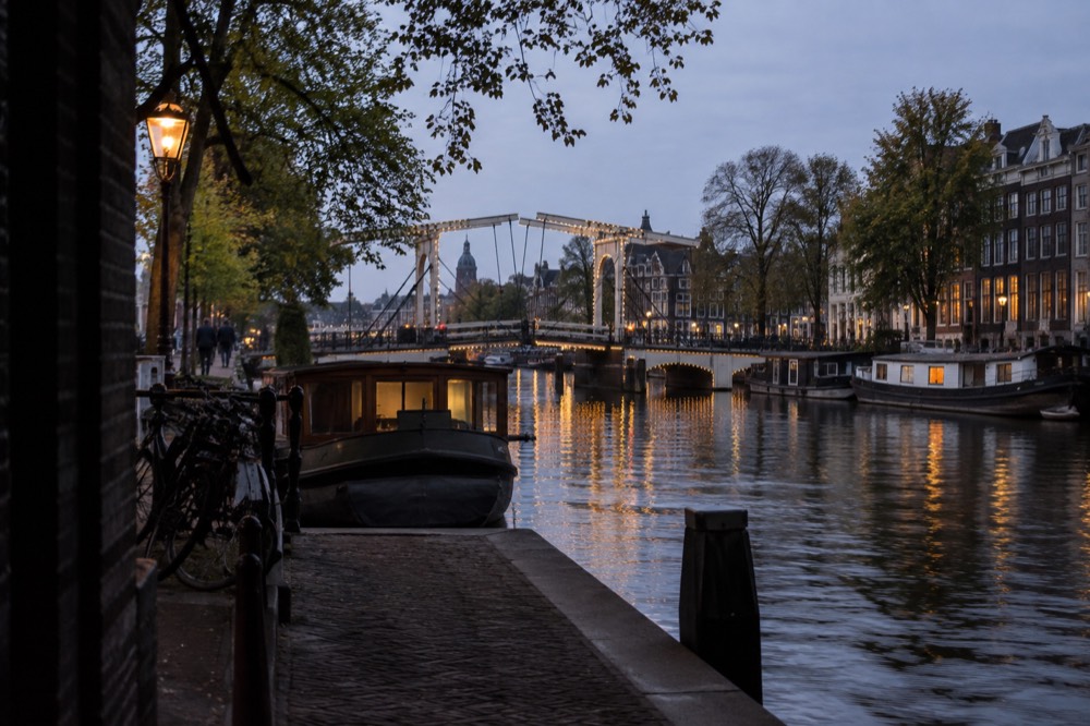 Evening light on an Amsterdam canal with a wooden drawbridge and moored houseboats
