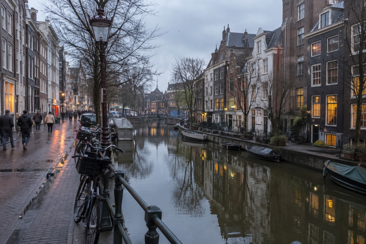 Canal houses reflected in still water along a quiet Amsterdam gracht at dusk