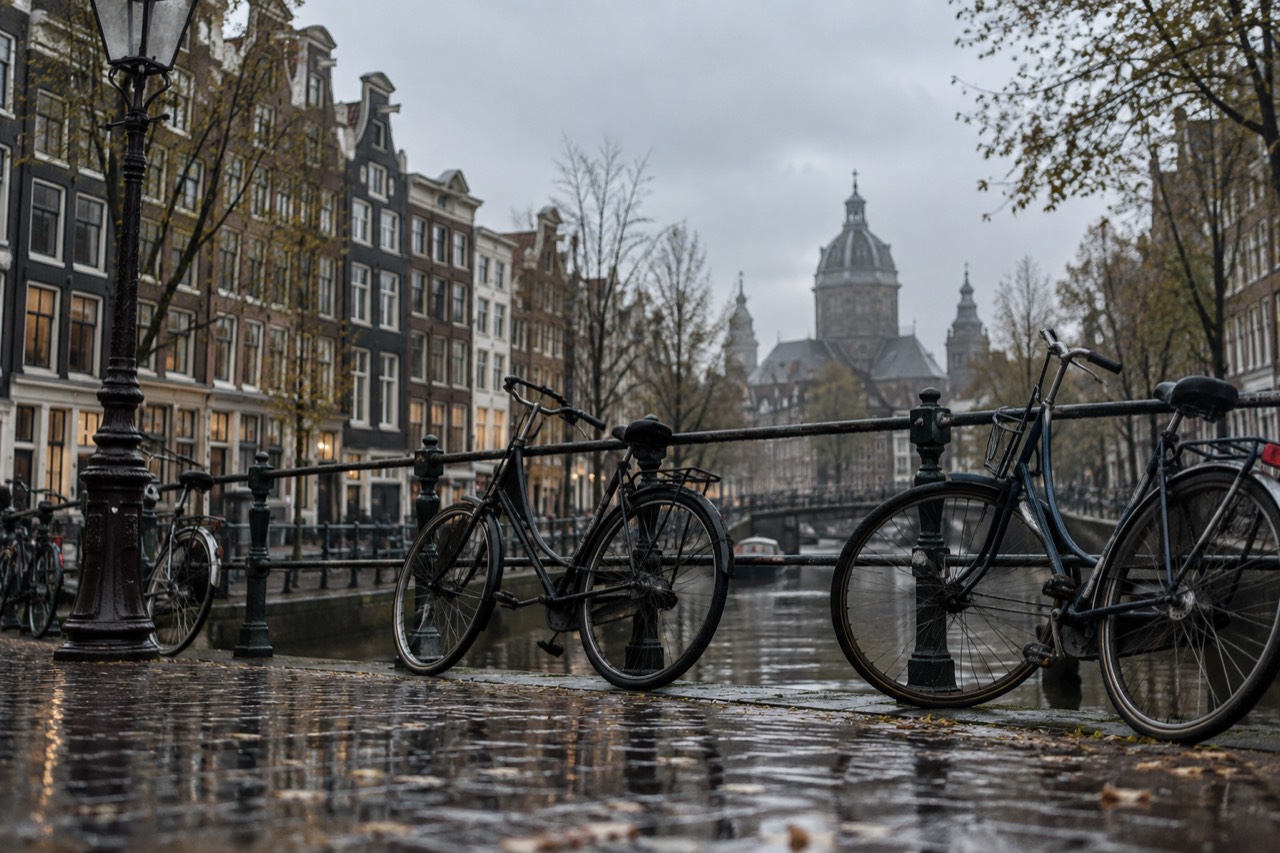 Canal houses along a quiet Amsterdam gracht with bicycles parked against a bridge railing