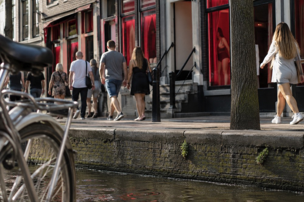 People walking past Red Light District, seen from across the street