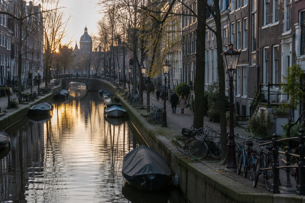 A quiet residential canal street in Amsterdam at dusk with parked bicycles