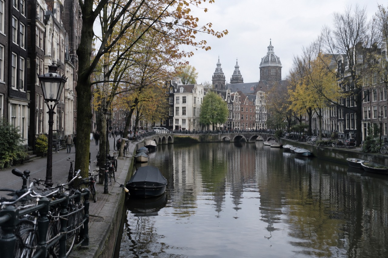 A quiet canal in central Amsterdam with narrow gabled houses reflected in the water