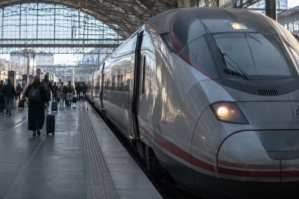 A high-speed train standing at an illuminated platform in a large European station