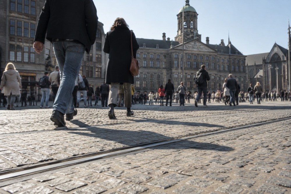 Weathered cobblestone street with a tram rail and people walking in sturdy shoes
