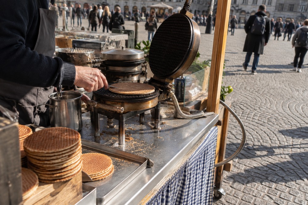 A street market stall with fresh stroopwafels being pressed on a hot iron