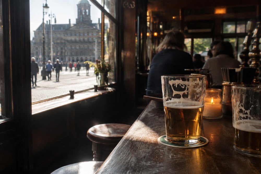 A candlelit wooden bar interior with beer glasses on the counter in an Amsterdam brown café