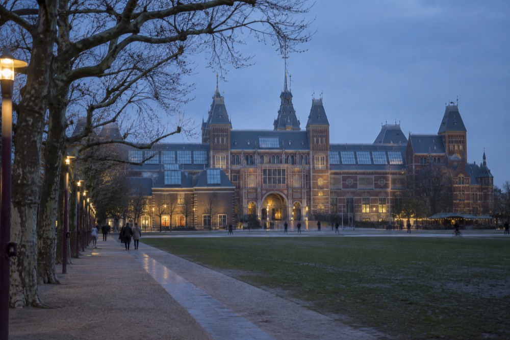 The Rijksmuseum facade seen across a quiet Museumplein in early morning light