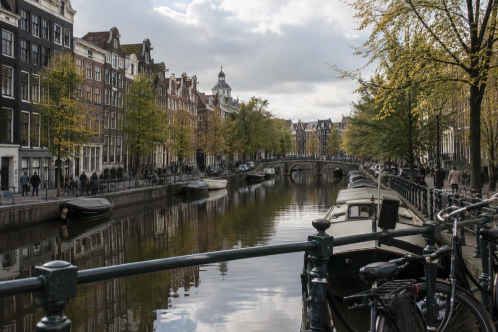 Amsterdam canal ring seen from a bridge, with narrow gabled houses reflected in still water