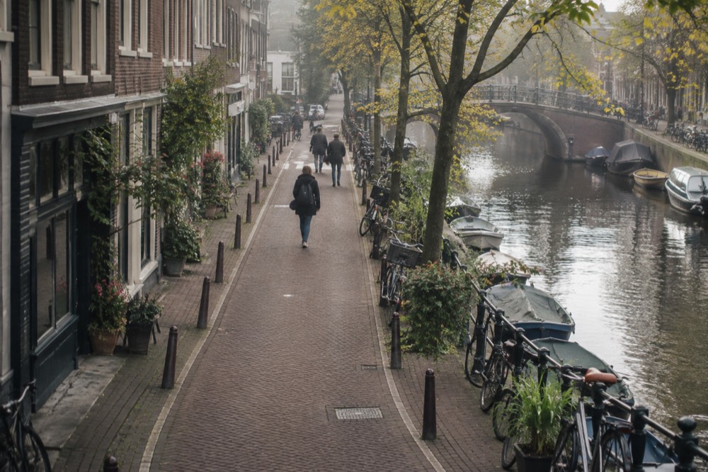 A quiet Jordaan street with small shops and bicycles parked against canal railings