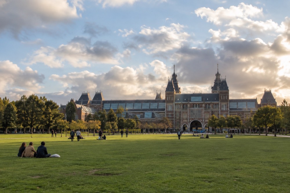 The Rijksmuseum building seen across a grassy Museumplein in late afternoon light
