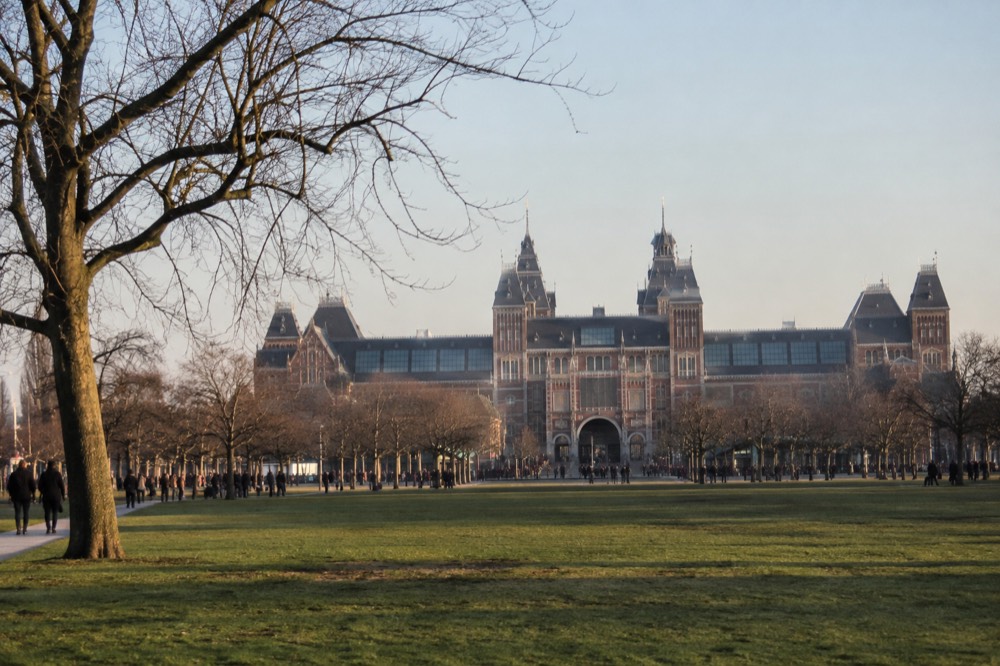 The grand neo-gothic facade of the Rijksmuseum seen across a green lawn at Museumplein