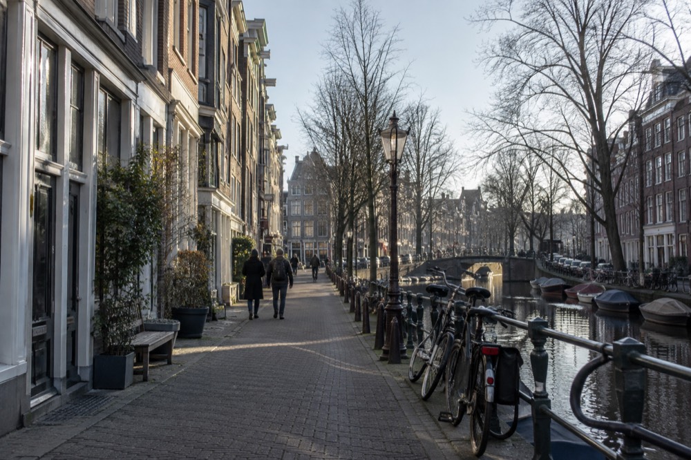 A narrow Jordaan street lined with small shops and bicycles parked against railings