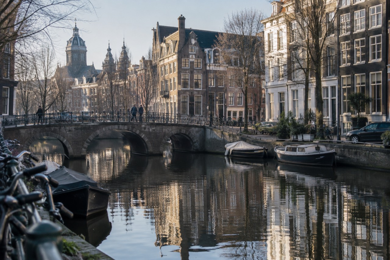 Amsterdam canal houses and bridges reflected in still morning water