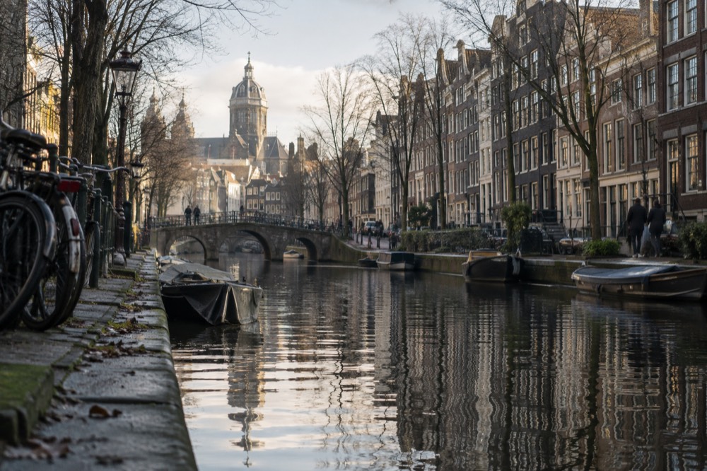 A quiet Amsterdam canal lined with narrow brick houses and moored bicycles
